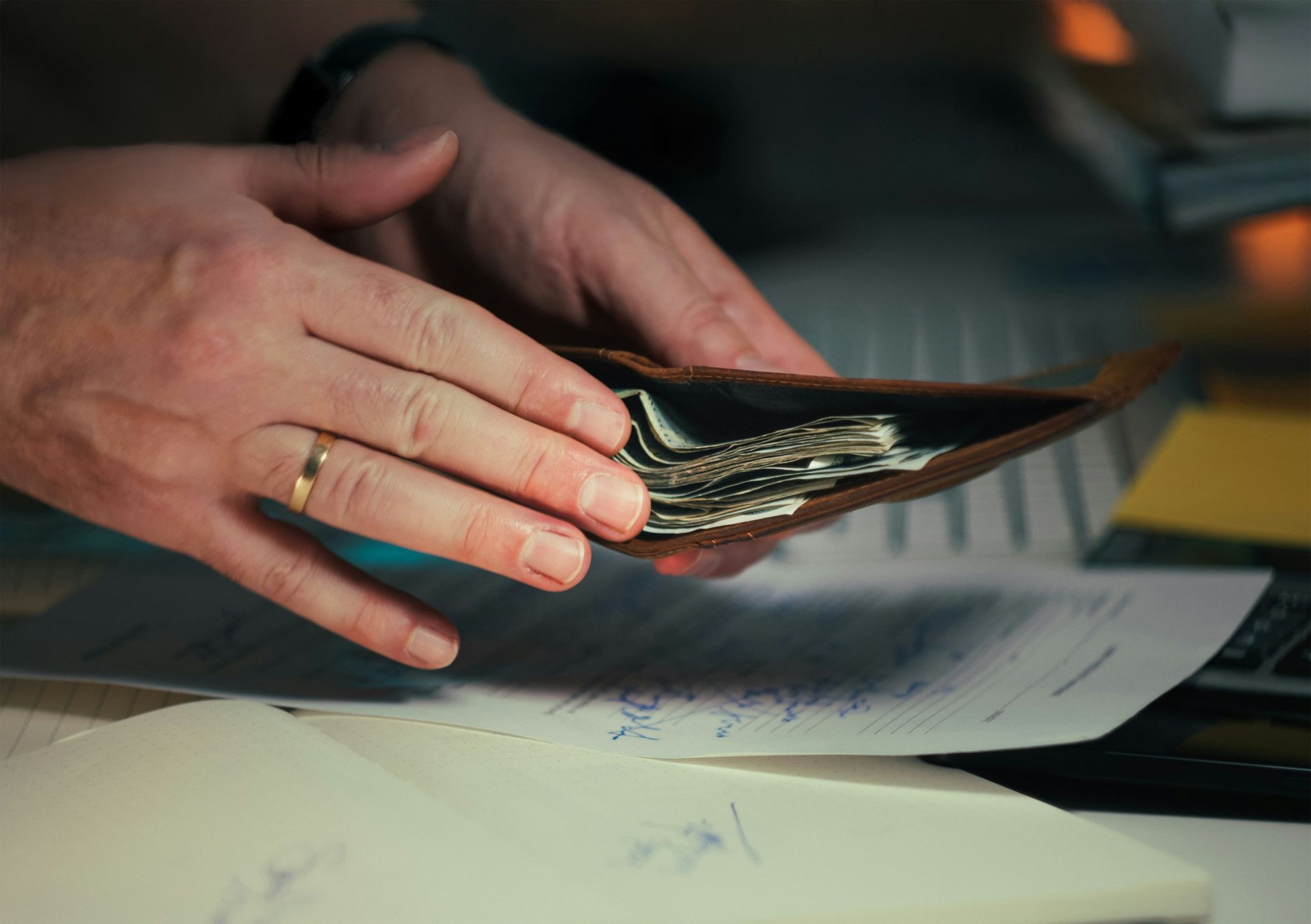 Hands holding an open wallet over signed paperwork